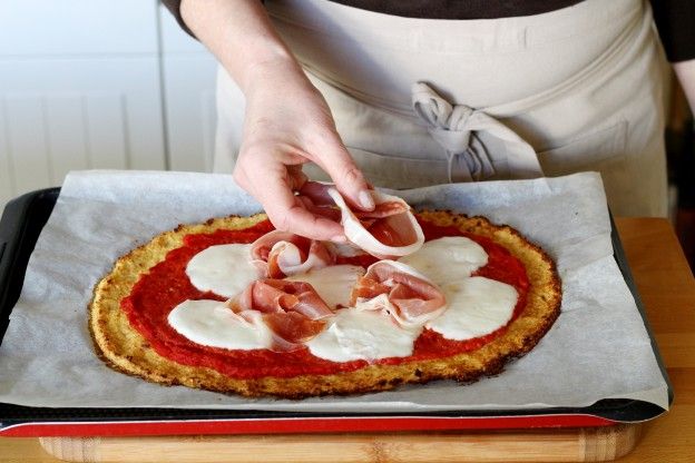 Den Schinken auf die Pizza geben