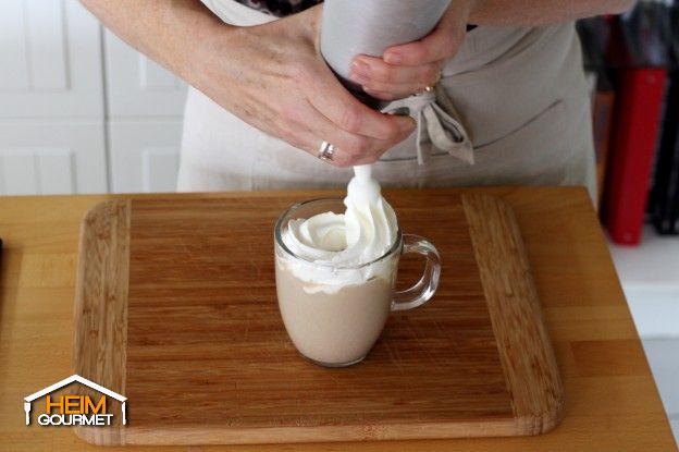 Die Schlagsahne auf den Kaffee geben