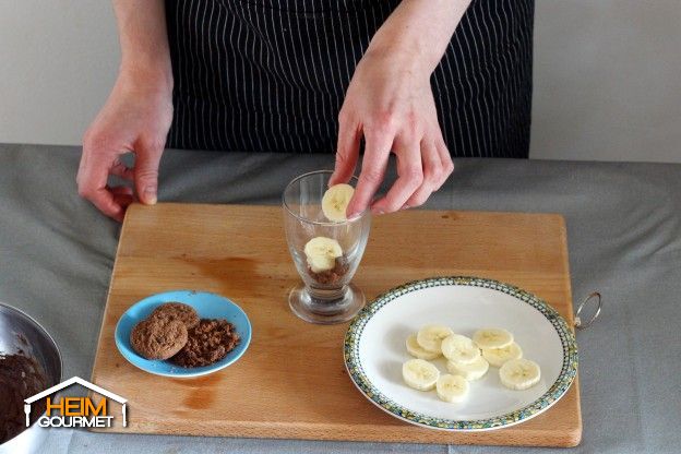 Den Boden der Dessertgläser mit den Kekskrümeln bestreuen und Bananenscheiben darauf legen.