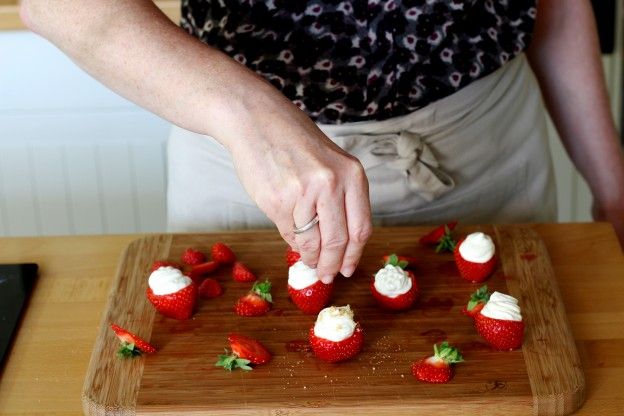 Die befüllten Erdbeeren mit den Keksbröseln bestreuen